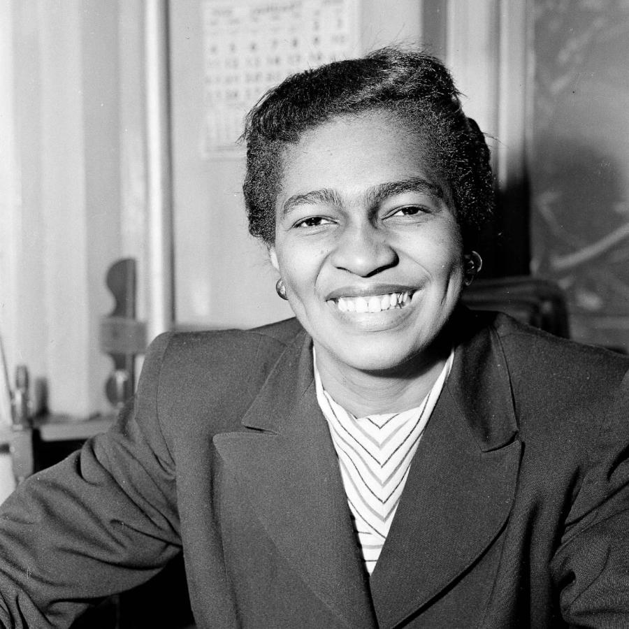 Copilot said:  Black-and-white portrait of seated person in jacket, smiling brightly indoors.