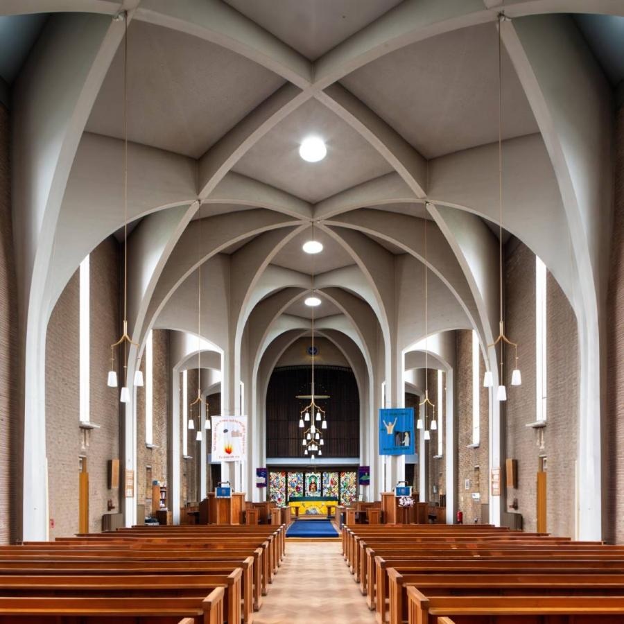Spacious church interior with vaulted arches, wooden pews, stained glass