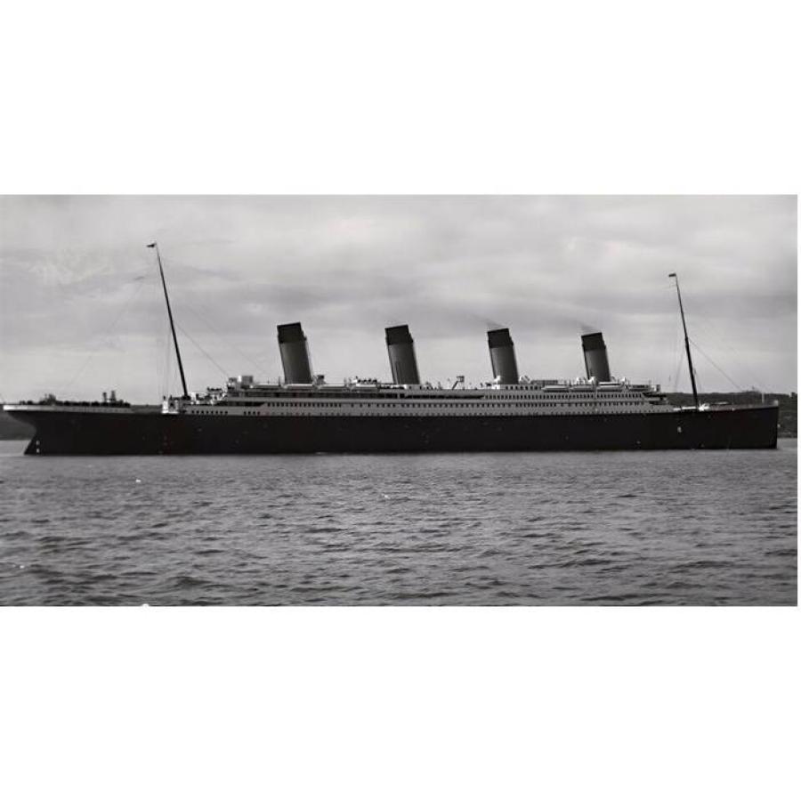 Large four-funnel ocean liner sailing on calm water beneath clouds.