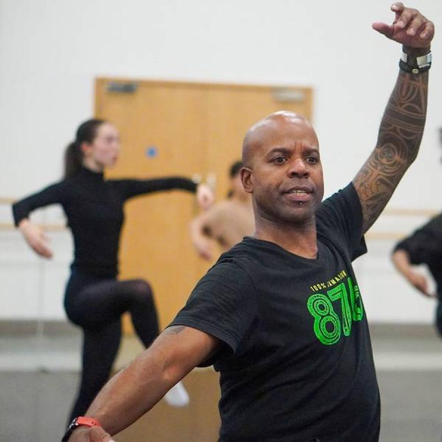 Dance instructor demonstrates movement while participants practice balanced poses together
