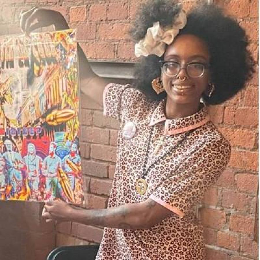 Artist holding a vibrant painting, wearing glasses and leopard-print clothing.
